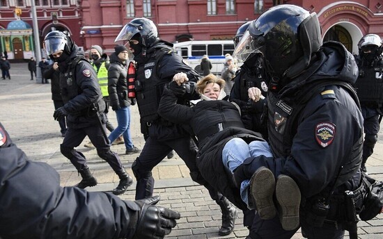 Police officers detain a woman during a protest against Russian military action in Ukraine, in Manezhnaya Square in central Moscow on March 13, 2022. (Photo by AFP)