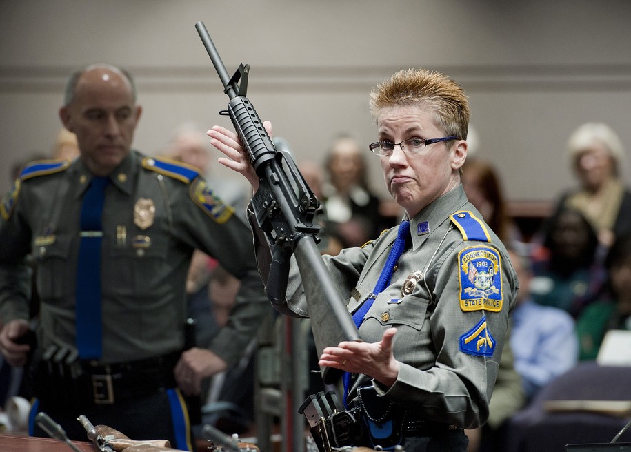 FILE - Firearms training unit Det. Barbara J. Mattson, of the Connecticut State Police, holds up a Bushmaster AR-15 rifle, the same make and model of gun used by Adam Lanza in the December 2012 Sandy Hook School shooting, during a hearing of a legislative subcommittee in Hartford, Conn., on Jan. 28, 2013. Citing a U.S. Supreme Court decision earlier this year, gun rights groups and firearms owners filed a new lawsuit Thursday, Sept. 29, 2022, in federal court in another attempt to overturn Connecticut's ban on certain semiautomatic rifles that was enacted in response to the Sandy Hook Elementary School shooting. (AP Photo/Jessica Hill, File)