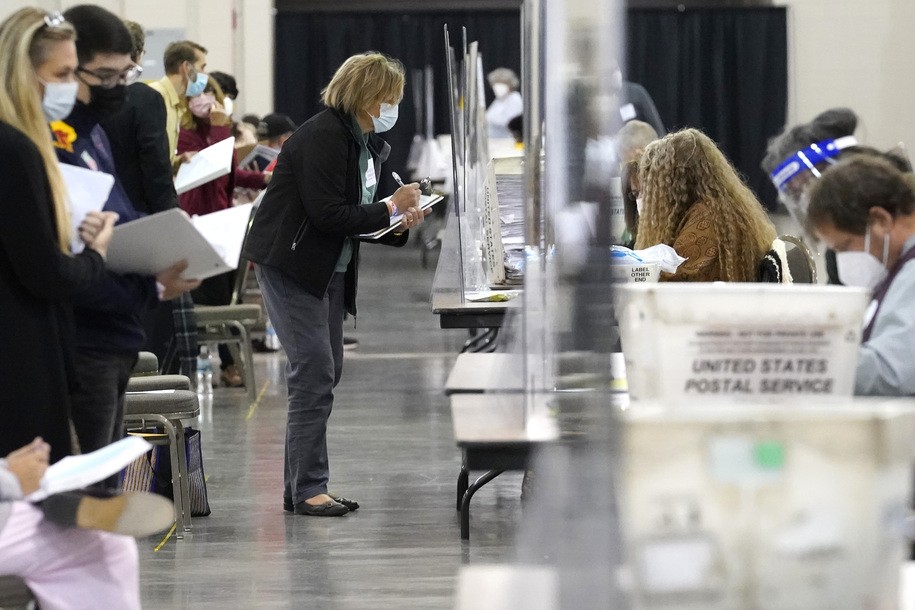 Recount observers watch ballots during a Milwaukee hand recount of Presidential votes at the Wisconsin Center, Nov. 20, 2020, in Milwaukee, Wis. A Wisconsin judge says he will order that the state elections commission reconsider a complaint filed against fake Republican electors who attempted in 2020 to cast the state’s electoral ballots for former President Trump. But this time, Dane County Circuit Judge Frank Remington said Monday, May 8, 2023 the commission must consider the complaint without the participation of one of its six commissioners who was also one of the fake electors. (AP Photo/Nam Y. Huh, file)