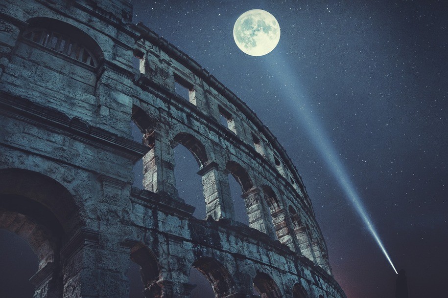 full moon over the ruins of the Colosseum, with a comet or meteor or possibly a contrail streaking toward lower right.