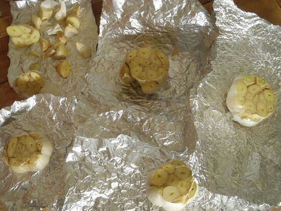 Ingredients for garlic soup with kale and pancetta - garlic heads, ready to be oiled, salted and peppered, wrapped in foil and roasted.