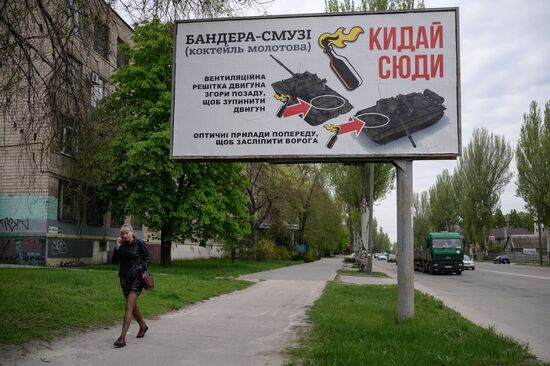 A woman walks past a billboard advising where to target tanks when throwing molotov cocktails, in Zaporizhzhia on April 29, 2022, on the 65th day of the Russian invasion of Ukraine. (Photo by Ed JONES / AFP) (Photo by ED JONES/AFP via Getty Images)