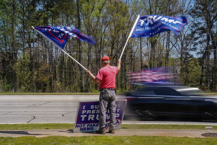 A supporter of former US president Donald Trump waves pro-Trump flags outside a stop on Florida Governor Ron DeSantis' nationwide book tour at Adventure Outdoors, the largest gun store in the country, on March 30, 2023 in Smyrna, Georgia. - DeSantis is widely expected to enter the race for the Republican presidential nomination. (Photo by Elijah Nouvelage / AFP) (Photo by ELIJAH NOUVELAGE/AFP via Getty Images)