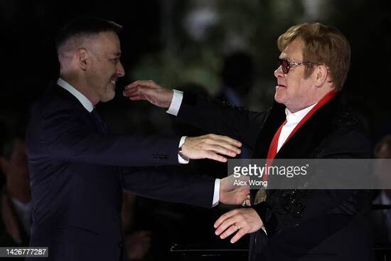 WASHINGTON, DC - SEPTEMBER 23: British singer-songwriter Sir Elton John (R) and his husband David Furnish (L) embrace each other after he was presented with the National Humanities Medal by U.S. President Joe Biden during an event at the South Lawn of the White House on September 23, 2022 in Washington, DC. President Joe Biden and first lady Jill Biden hosted the event titled â€œA Night When Hope and History Rhyme,â€ to â€œcelebrate the unifying and healing power of music, commend the life and work of Sir Elton John, and honor the everyday history-makers in the audience, including teachers, nurses, frontline workers, mental health advocates, students, LGBTQ+ advocates and more.â€ (Photo by Alex Wong/Getty Images)