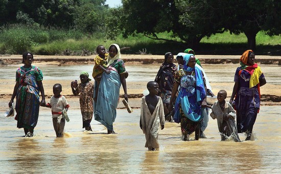 DARFUR, SUDAN- SEPTEMBER 9:  Sudanese refugees from the violence plagued Darfur region flee across an intermittent stream marking the international border with neighbouring Chad as they head to refugee camps in already swollen villages in the area on September 9, 2004 in Darfur, Sudan.  United States Secretary of State Colin Powell told a U.S. congressional committee this week that the ethnic violence in Sudan amounts to "genocide" and a U.S. sponsored resolution calling for sanctions against the Sudan government was debated at the United Nations in New York. (Photo by Scott Nelson/Getty Images)