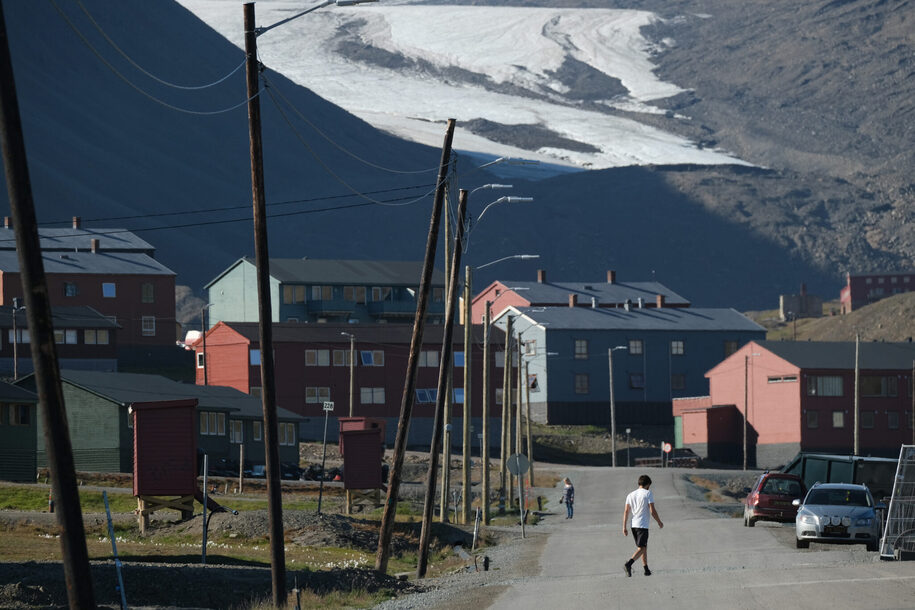 LONGYEARBYEN, NORWAY - JULY 30: A man wearing shorts and a t-shirt walks in the town center as the melting Longyear glacier looms behind during a summer heat wave on Svalbard archipelago on July 30, 2020 in Longyearbyen, Norway. Svalbard archipelago, which lies approximately 1,200km north of the Arctic Circle, is currently experiencing a summer heat wave that set a new record in Longyearbyen on July 25 with a high of 21.7 degrees Celsius. Global warming is having a dramatic impact on Svalbard that, according to Norwegian meteorological data, includes a rise in average winter temperatures of 10 degrees Celsius over the past 30 years, creating disruptions to the entire local ecosystem.  (Photo by Sean Gallup/Getty Images)